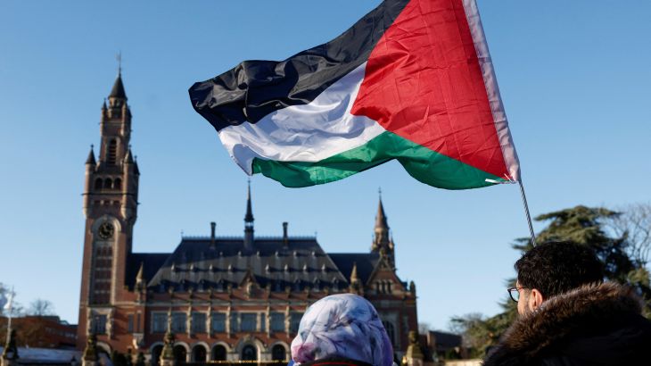 Protesters hold a Palestinian flag as they gather outside the International Court of Justice (ICJ)