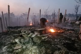 Rohingya refugees look through the debris of their houses after a fire in Bangladesh