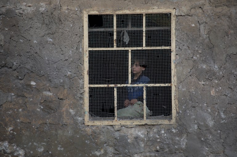 A child looks warily at the street from the window of his house, where he is hiding from the repeated bombing by regime forces on Darat Azza in the western countryside of Aleppo on the first day of 2024.