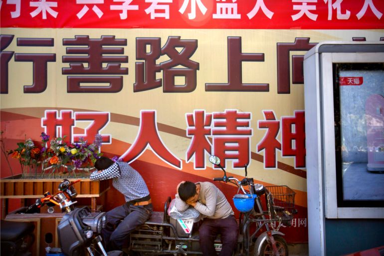 Construction workers take a nap in front of a billboard outside of a construction site in the central business district in Beijing, Friday, Sept. 22, 2017. China's Finance Ministry on Friday criticized the cut in the Standard &amp; Poor's rating agency's credit rating on Chinese government borrowing as a "wrong decision" and said it ignores the country's economic strength. (AP Photo/Mark Schiefelbein)