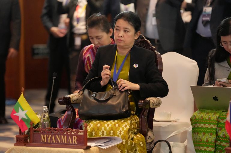 Myanmar's ASEAN Permanent Secretary Marlar Than Htike at the group's meeting in Laos. She's seated at the chair for Myanmar. A low table in front has a wooden placeholder reading Myanmar