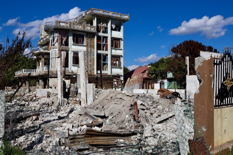 A pile of rubble in front of a damaged four storey building