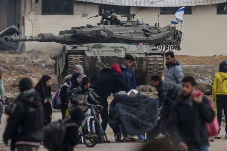 epa11109089 Internally displaced Palestinians move past Israeli tanks after the Israeli army told residents of Khan Yunis camp to leave their homes and head towards Rafah camps near the Egyptian border, southern Gaza Strip, 27 January