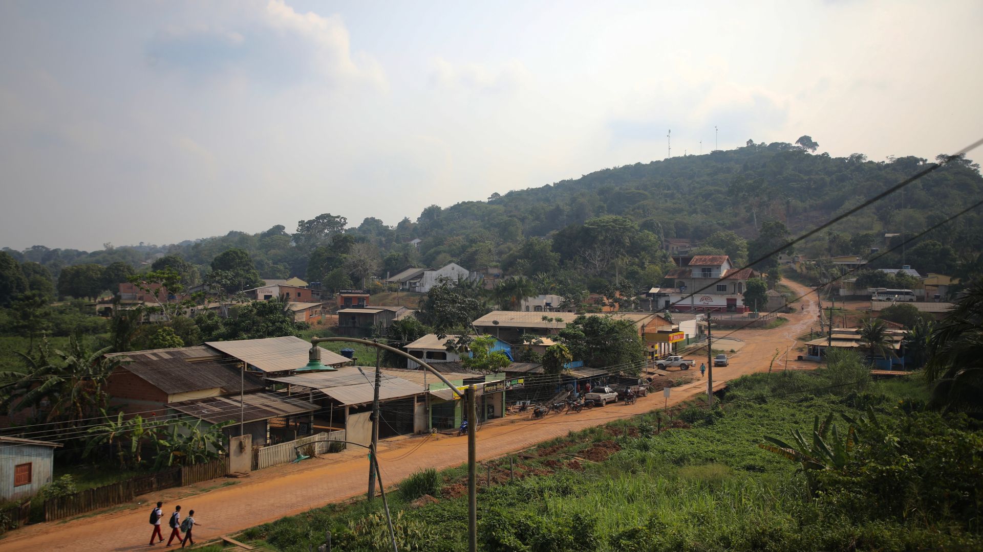 A dirt road, lined with modest homes, runs through the Amazon rainforest.