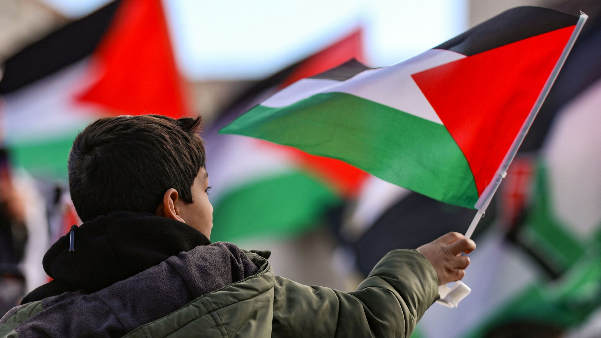 A boy holds a Palestinian flag during a march for Gaza, in Washington, DC