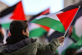 A boy holds a Palestinian flag during a march for Gaza, in Washington, DC