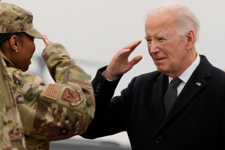 Biden and US soldier in military fatigues exchange army salute