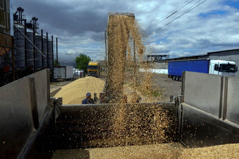 A worker loads a truck with grain at a terminal