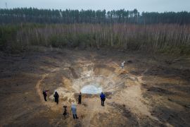 People stand around a crater crated by a Russian missile strike, amid Russia’s attack on Ukraine, in the village of Buda-Babynetska, outside Bucha, near Kyiv, Ukraine February 15, 2024. REUTERS/Thomas Peter