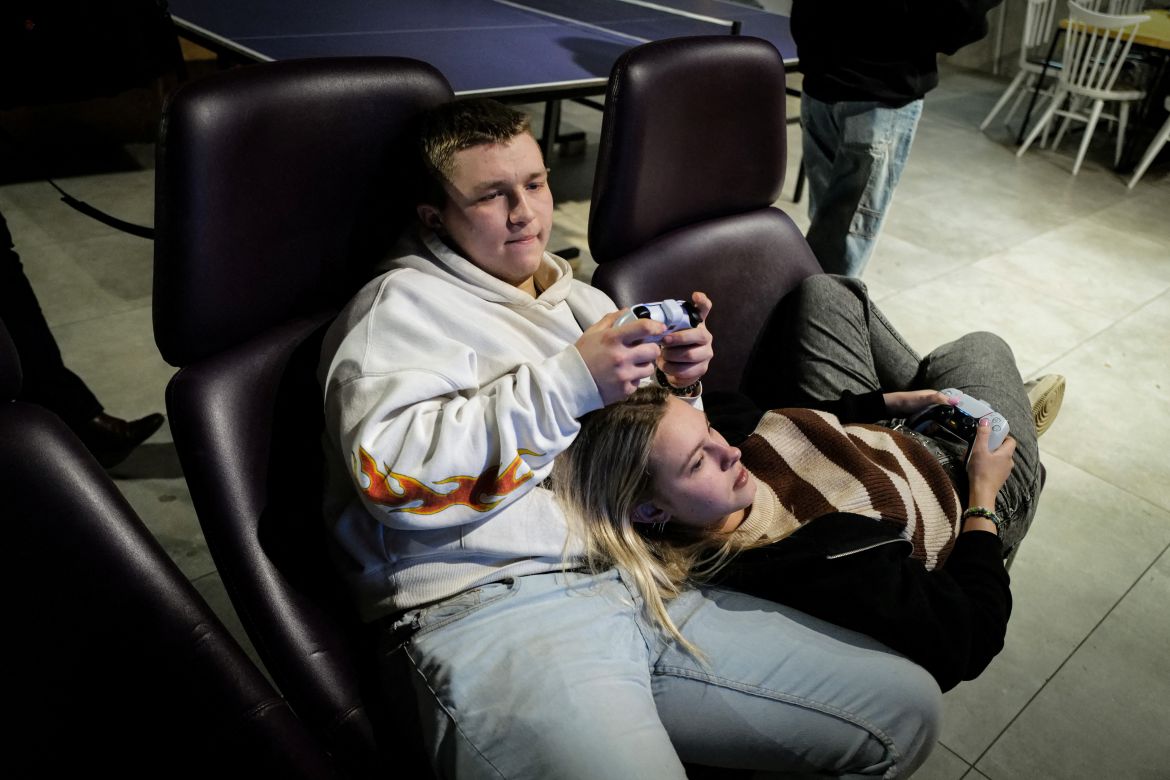 Dariia Vynohradova, 17, from Kharkiv and her boyfriend Dmytro Demchevskyi, 18, from Yuzhnoukrainsk, play a video game at Blue Trainers, a community space in a shopping mall in Gdansk, Poland, February 15