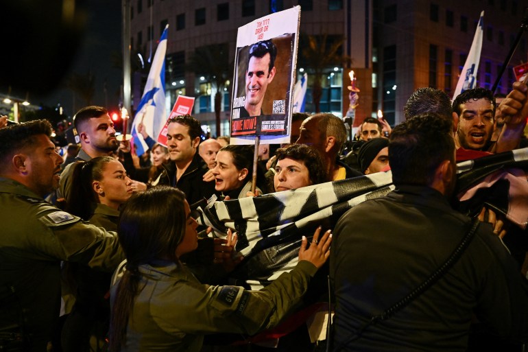 People stand in front of police officer during a protest against Israeli Prime Minister Benjamin Netanyahu's government