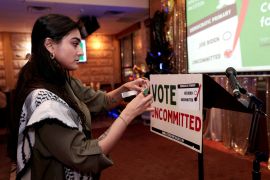 Activist Natalia Latif tapes a &#039;Vote Uncommitted&#039; sign on the speaker&#039;s podium during a primary election night gathering in Dearborn, Michigan, on February 27 [Rebecca Cook/Reuters]