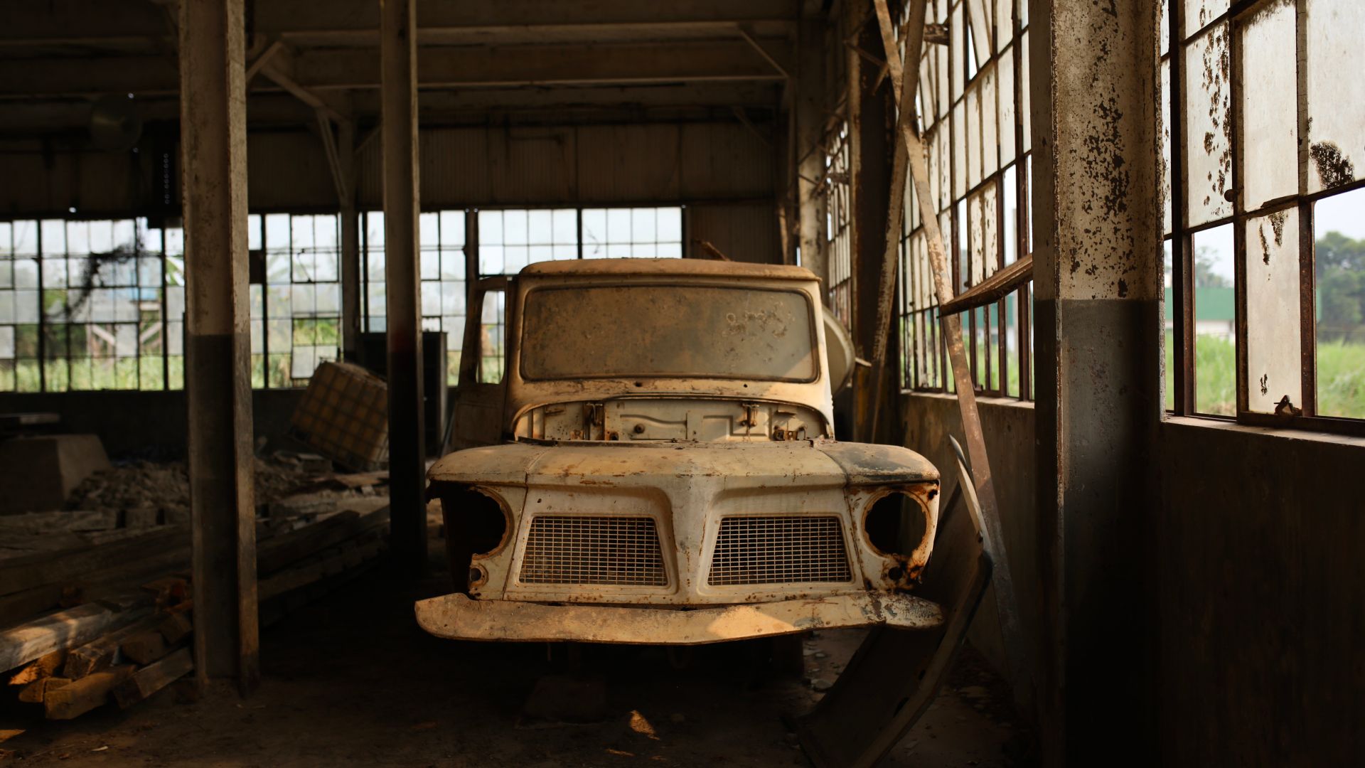A rusted, antique truck sits in an abandoned warehouse.