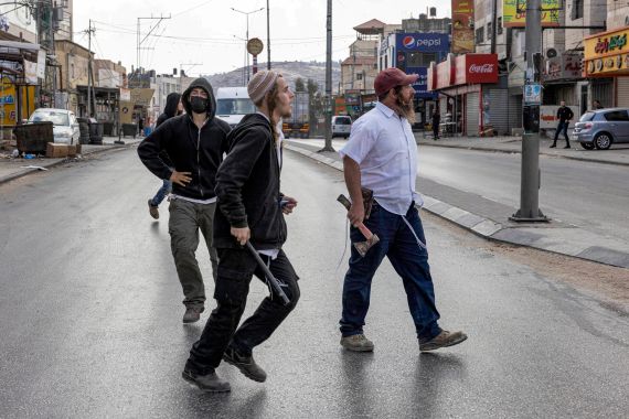Illegal Israeli settlers walk with batons and axes along a street during clashes in which Israeli settlers attacked Palestinian residents and shops in the town of Huwara in the occupied West Bank on October 13, 2022. (Photo by Oren ZIV / AFP)