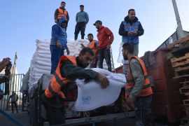 Palestinians receive bags of flour at the United Nations Relief and Works Agency for Palestine