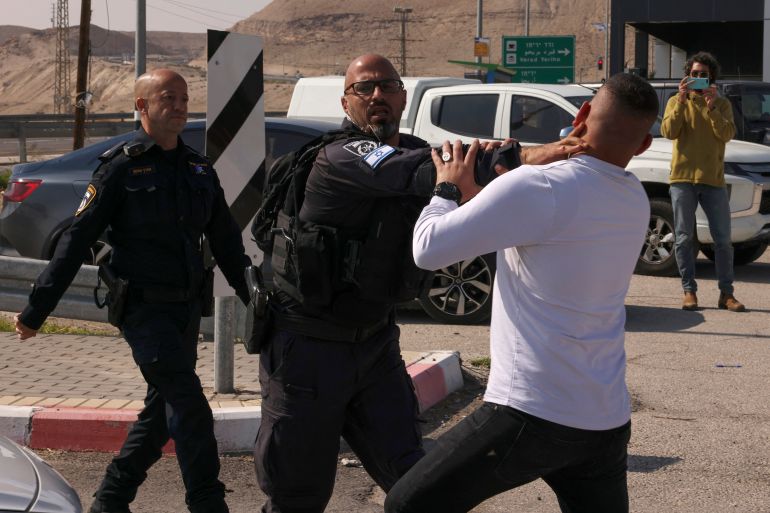 Members of Israeli security forces arrest a demonstrator as Israeli and Palestinian activists protest Israel's ongoing war in Gaza, at a junction leading to Jericho city in the occupied West Bank on February 9, 2024. (Photo by HAZEM BADER / AFP)