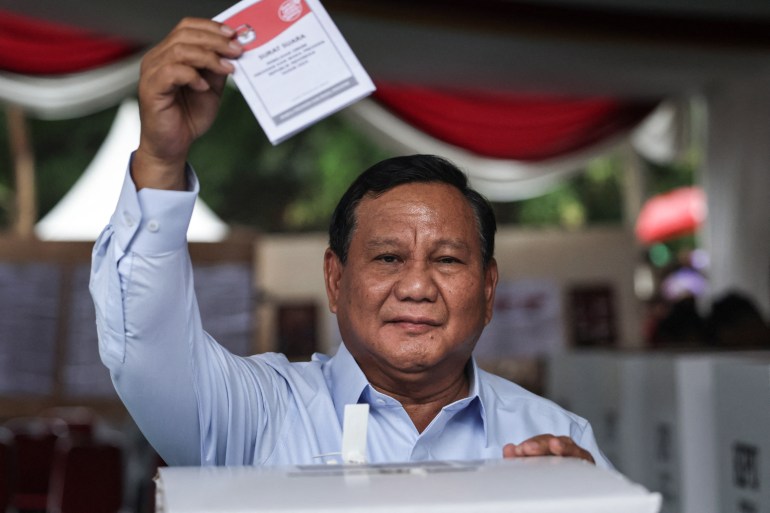 Prabowo holding up his folded ballot paper before putting it in the box