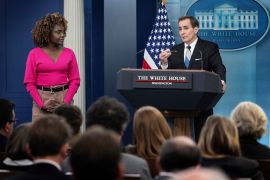 John Kirby at the White House briefing, He's standing at a lectern. Journalists are in front of him. White House Press Secretary Karine Jean-Pierre is next to him.