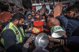Displaced Palestinians gather to receive food at a government school in Rafah in the southern Gaza Strip on February 19, 2024.