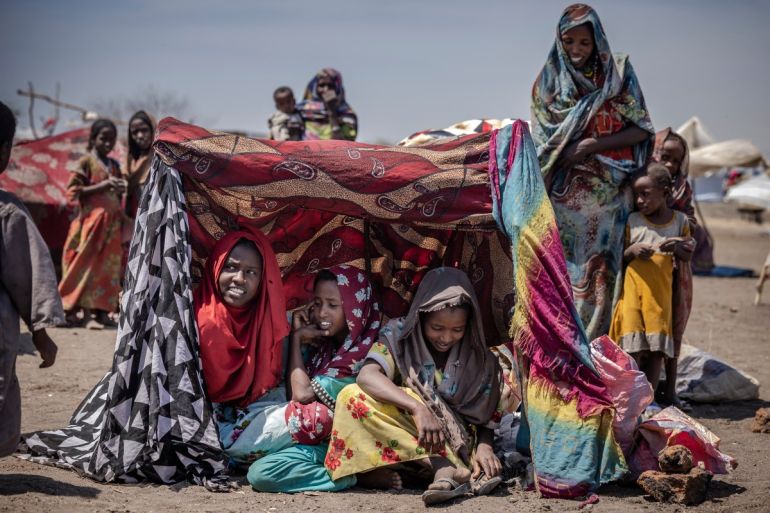 Sudanese girls who have fled from the war in Sudan gather under a shade at a Transit Centre for refugees in Renk