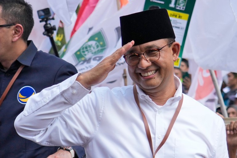 Anies Baswedan. He is saluting to the crowd and smiling