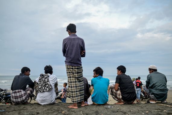 Rohingya men standing on a beach looking out to sea