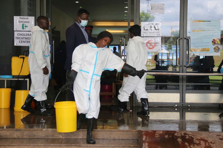 A worker carries a bucketfull of disinfectant at a cholera treatment centre, in Lusaka, Zambia, Friday, Jan 12, 2024. The country is reeling from a major cholera outbreak that has killed more than 400 people and infected more than 10,000, leading authorities to order schools across the country to remain shut after the end-of-year holidays. (AP Photo)