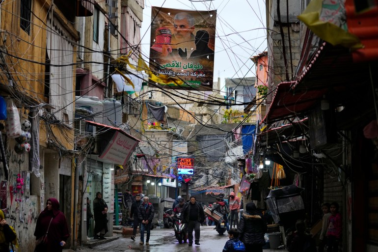 Palestinians walk under a poster that shows Yahya Sinwar, head of Hamas in Gaza, on a street inside the Bourj al-Barajneh Palestinian refugee camp, south of Beirut, Lebanon, Monday, Feb. 5, 2024. There are nearly 500,000 Palestinian refugees registered in Lebanon, although the actual number in the country is believed to be around 200,000, as many have emigrated but remain on UNRWA's roster. (AP Photo/Bilal Hussein)