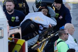 A woman on a stretcher is loaded into an ambulance.
