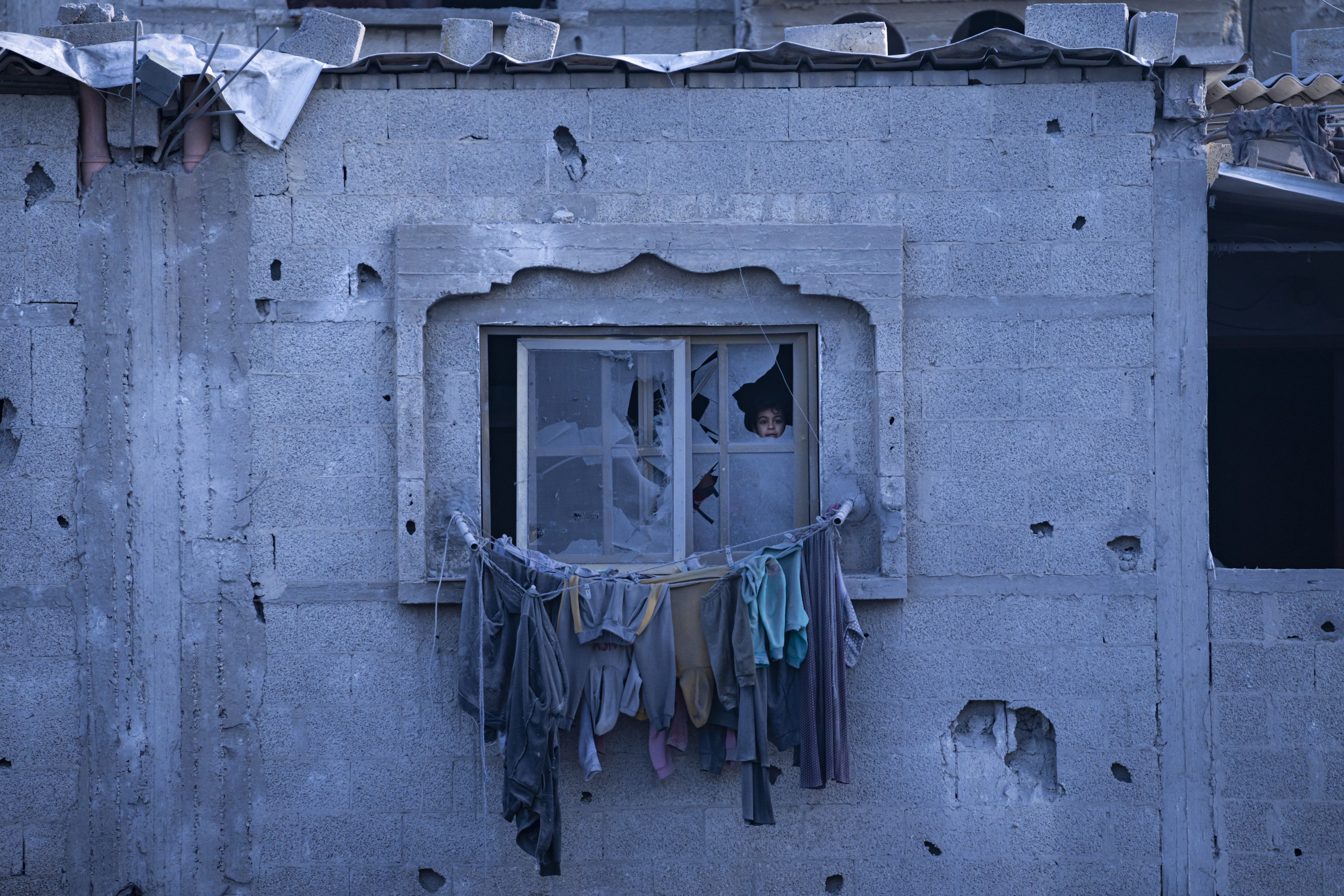 A child looks through a broken window in Rafah, Gaza Strip, Wednesday, Feb. 21