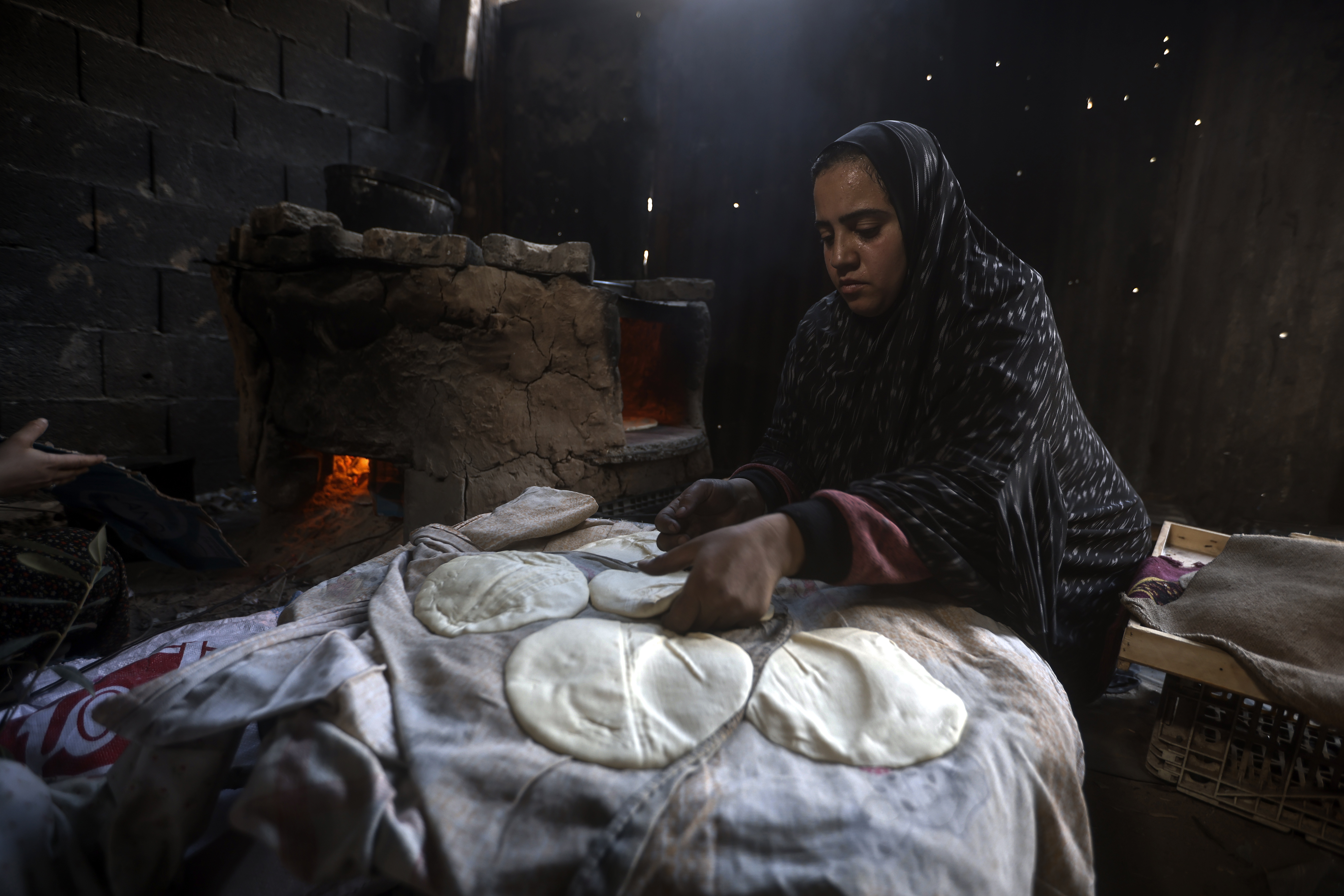 A Palestinian woman displaced by the Israeli ground offensive on the Gaza Strip bake bread at a makeshift tent camp in Rafah, Gaza Strip, Monday