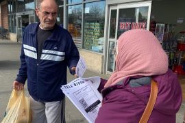 A volunteer hands out a flyer at a grovery store in Dearborn, Michigan. [Malak Silmi/Al Jazeera]