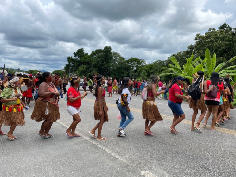 A line of Indigenous activists marches in a circle in the middle of a roadway in Bahia, a state in Brazil.