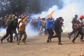 Farmer protesters running from tear gas by riot police.