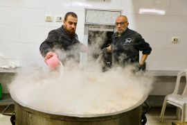 Two chefs start the chicken cooking [Mosab Shawer/Al Jazeera]
