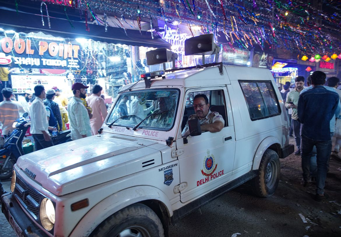 A police van passes through the food street in Shaheen Bagh during Iftar. [Meer Faisal/Al Jazeera]