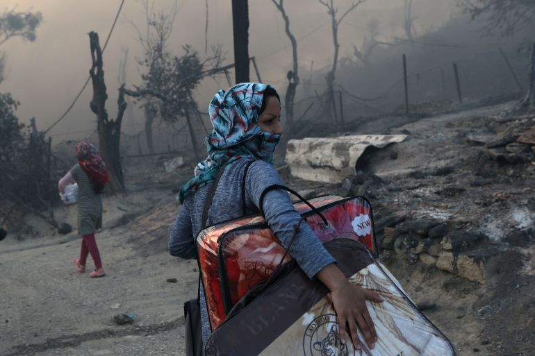 A migrant carries her belongings following a fire at the Moria camp for refugees and migrants on the island of Lesbos, Greece, September 9, 2020. REUTERS/Elias Marcou/File photo TPX IMAGES OF THE DAY SEARCH "GLOBAL POY" FOR THIS STORY. SEARCH "REUTERS POY" FOR ALL BEST OF 2020 PACKAGES.
