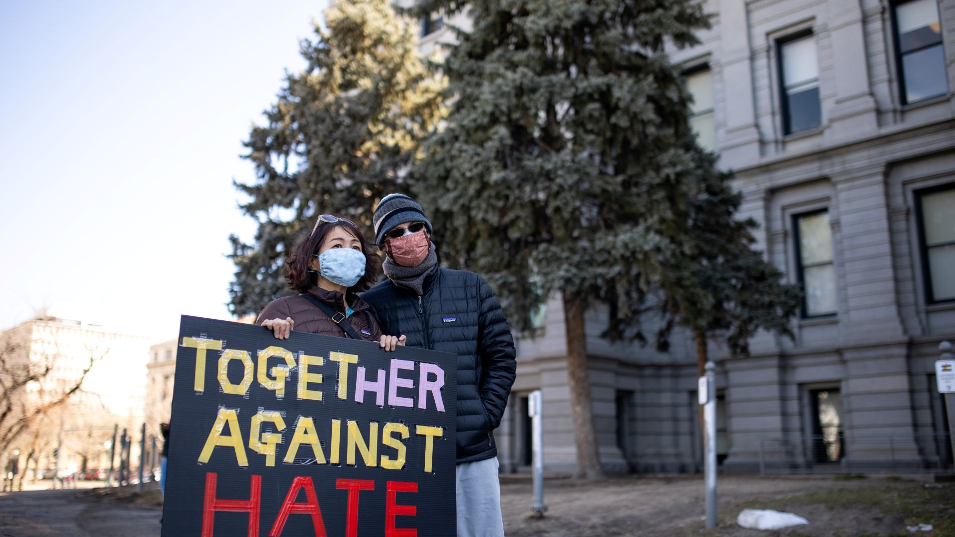 A woman holds a sign that reads 'Together Against Hate' during a wave of anti-Asian hate during the COVID-19 pandemic