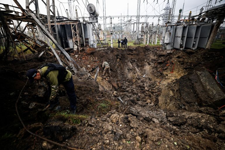 Investigators inspect a crater left by a Russian missile strike at an electrical transformer facility, amid Russia's attack on Ukraine, in Kharkiv
