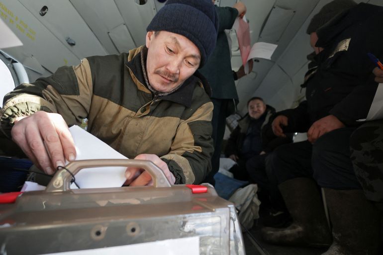 Reindeer herder Dmitry Neustroyev, 50, casts his ballot inside a helicopter during early voting in Russia's presidential election, as members of an electoral commission visit a remote farm in the Sakha Republic, also known as Yakutia, in the northeastern part of Siberia, Russia, February 29, 2024