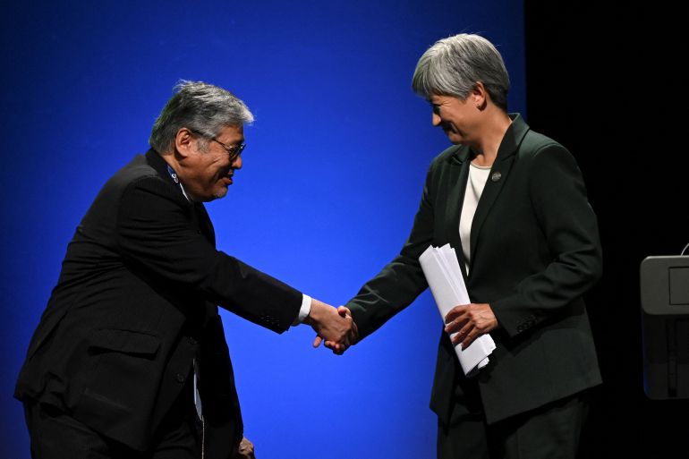 two people shake hands next to blue background