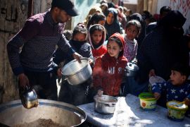 Palestinian children wait to receive food cooked by a charity kitchen amid famine, in Rafah, in the southern Gaza Strip on March 5, 2024 [Reuters/Mohammed Salem]