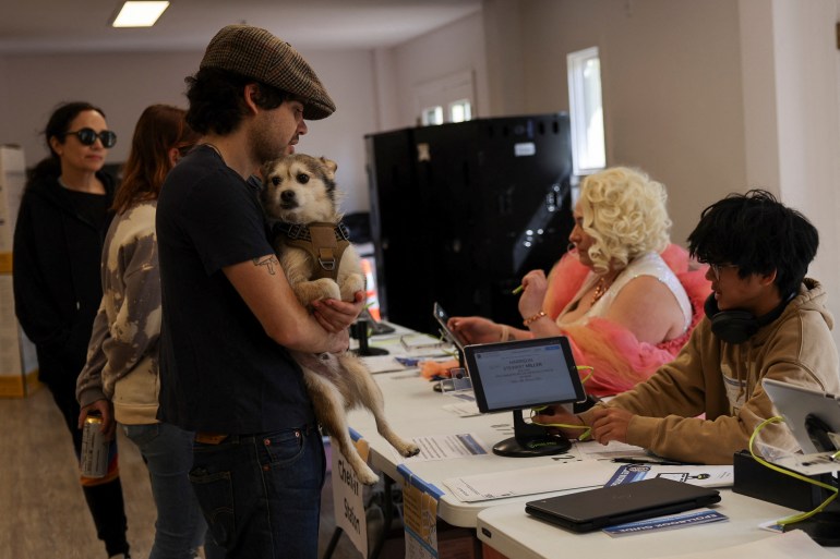 Man holding a dog as he receives his ballot