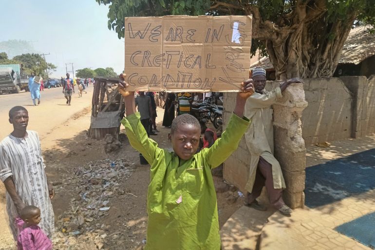 A boy holds a sign to protest against, what a teacher, local councilor and parents said, the kidnapping of hundreds school pupils by gunmen after the Friday prayer, in Kaduna, Nigeria March 8, 2024