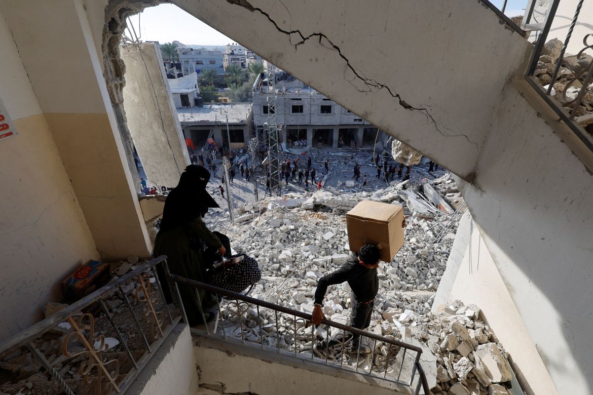 Palestinians carry belongings at the site of an Israeli air strike on a building