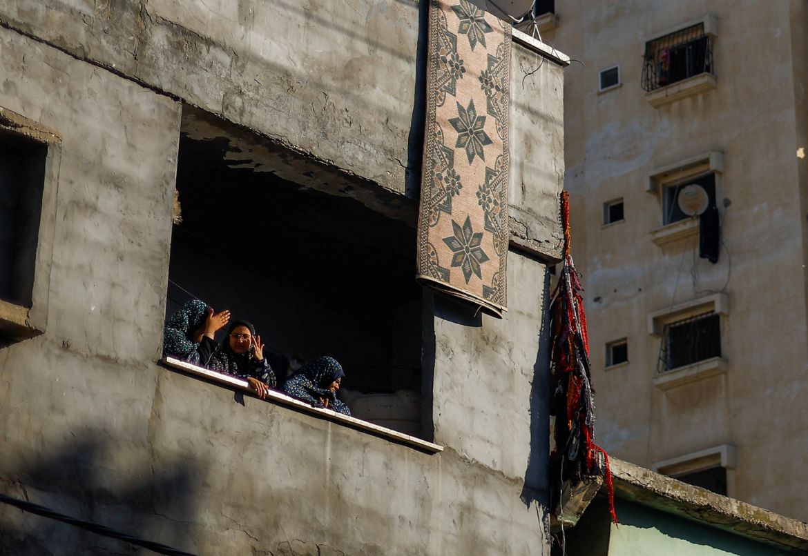 Palestinian women look on from inside a building damaged by an Israeli air strike