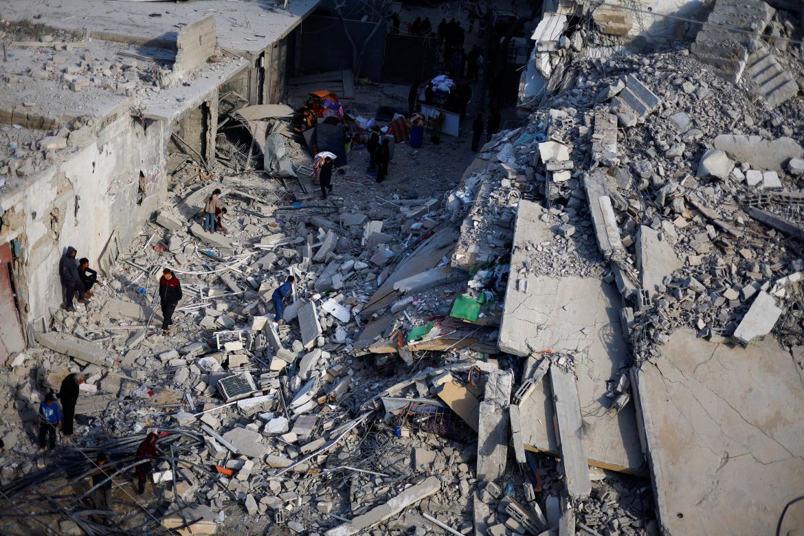 Palestinians inspect the site of an Israeli air strike on a building in Rafah