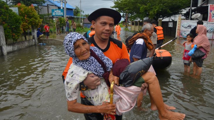 A Local Disaster Management Agency (BPBD) officer evacuates an elderly woman from a residential area affected by floods due to heavy rains, in Padang