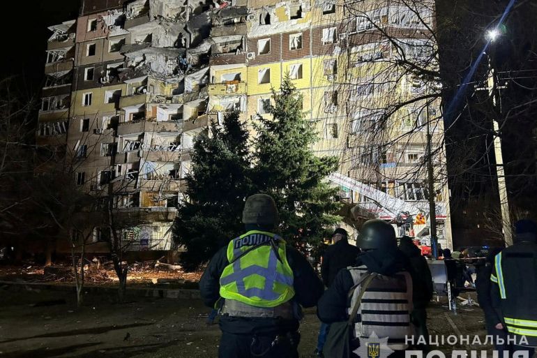 Police officers stand in a front of an apartment building damaged by a Russian missile strike