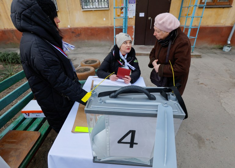 Local residents gather at a mobile polling station during the early voting in Russia’s presidential election